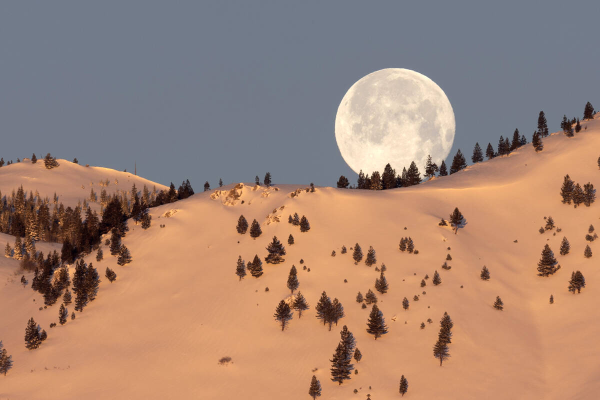 February’s Snow Moon sets behind the snow-covered mountains on Monday, Feb. 6, 2023, in Carso ...