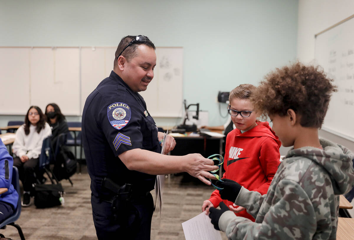 Clark County School District Police Officer Juan Wibowo hands a bracelet to Samuel Watson, 11, ...