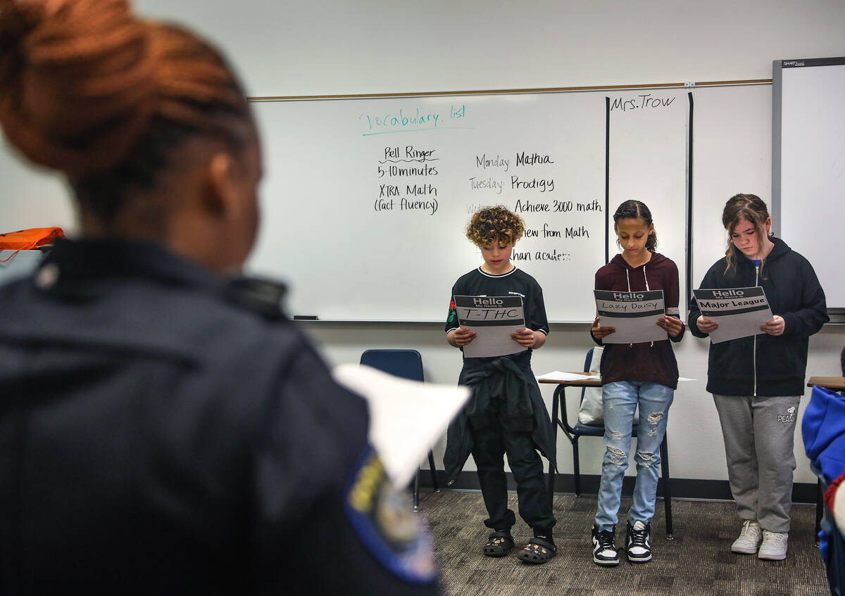 Clark County School District Police Officer Artesia Henry leads students James Palang, 11, from ...