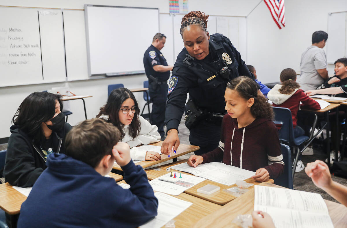 Clark County School District Police Officer Artesia Henry helps Eliza Coulson, 12, from right, ...