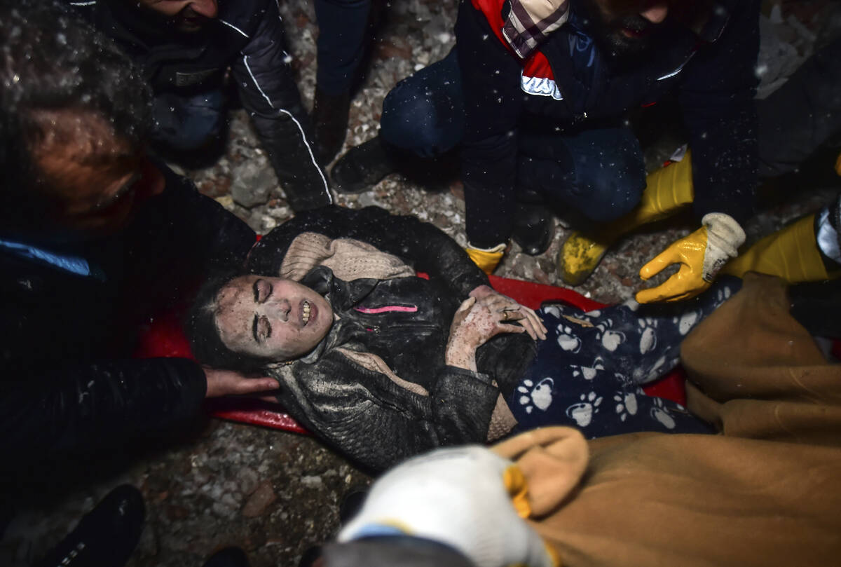 Rescue workers and medics carry a woman out of the debris of a collapsed building in Elbistan, ...