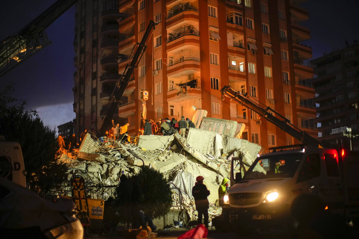 Emergency team members search for people in a destroyed building in Adana, Turkey, Tuesday, Feb ...