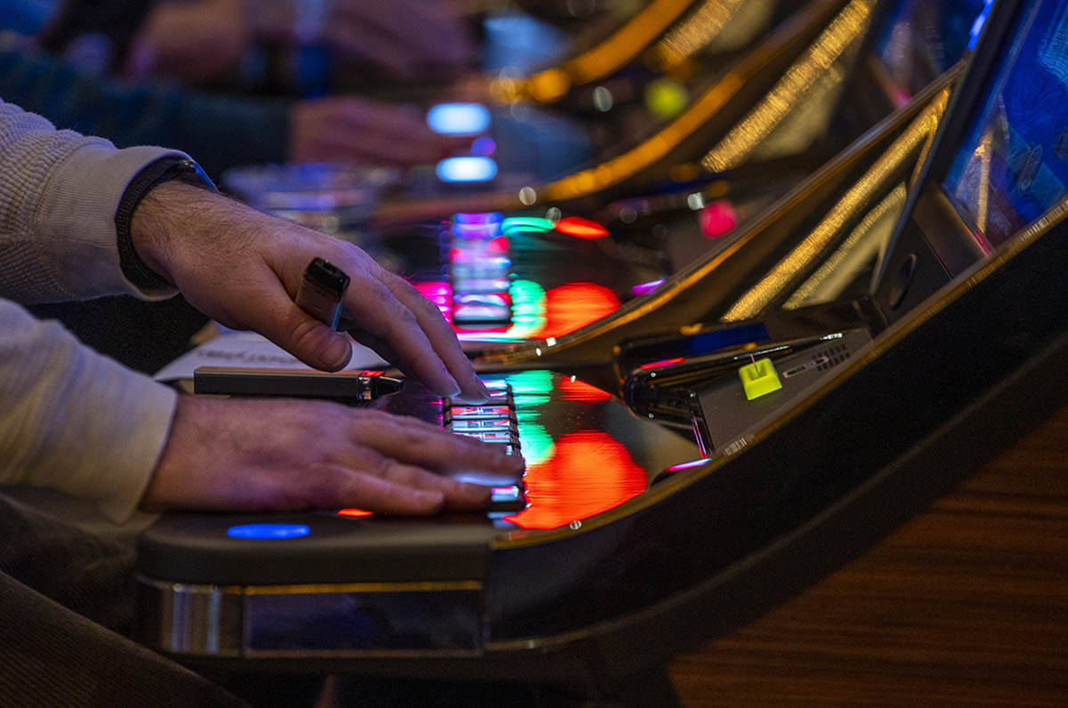 A visitor plays a slot machine with others nearby at Red Rock Casino on Tuesday, Dec. 26, 2021, ...