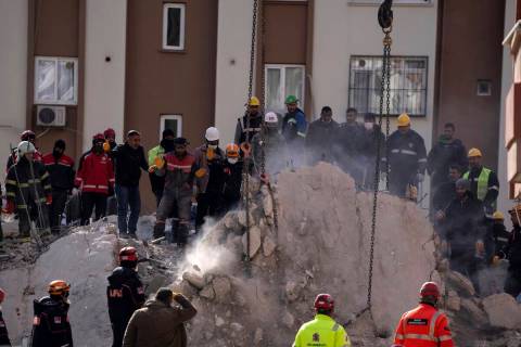 Firefighters and rescue teams search for people in a destroyed building, in Adana, southern Tur ...