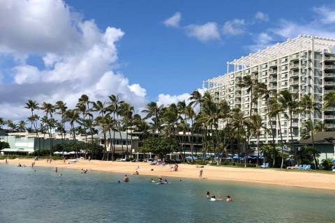 People relax on the beach and in the water in front of the Kahala Hotel & Resort in Honolulu on ...