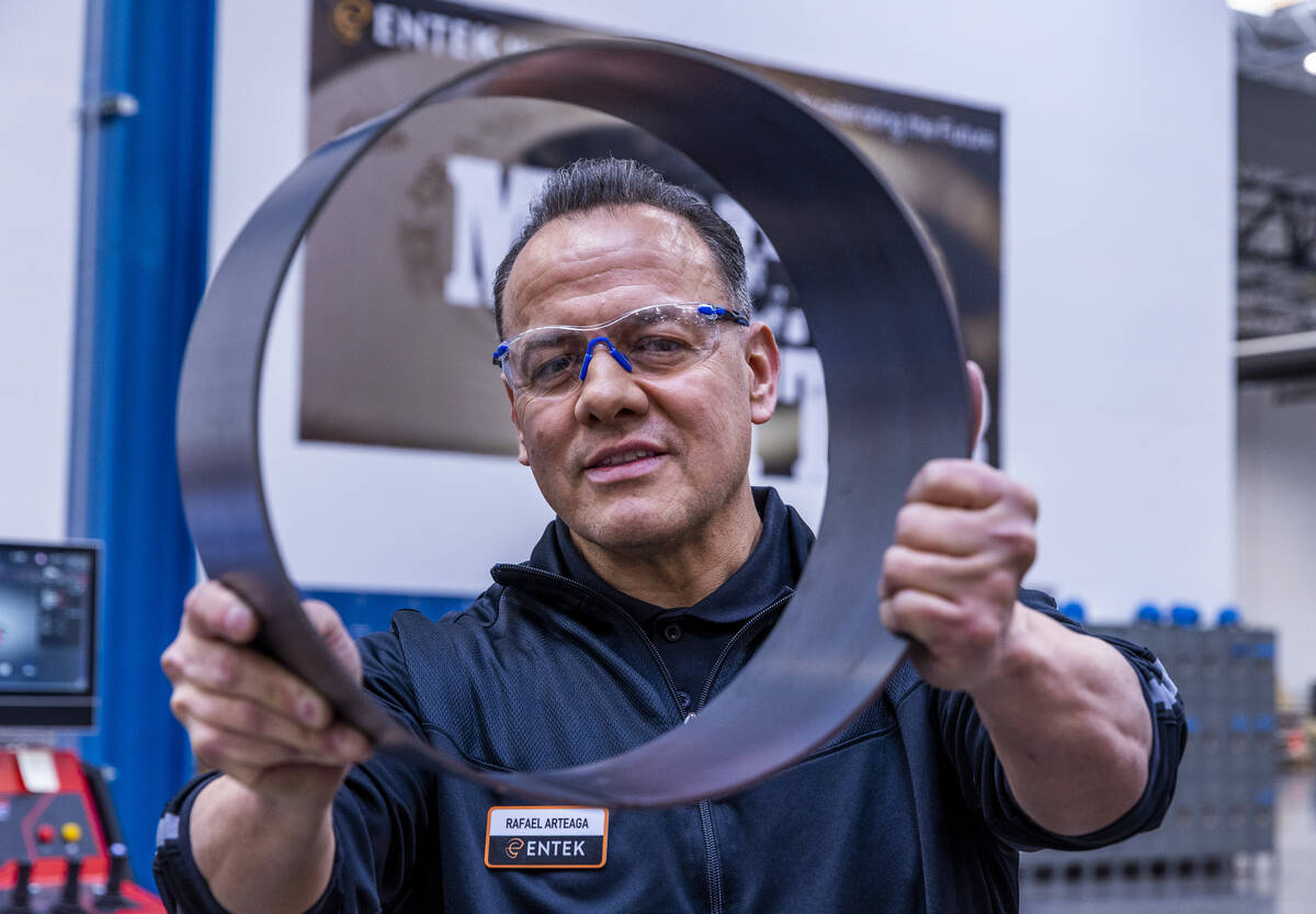 ENTEK's Rafael Arteaga looks to a new cylindrical piece he pressed during a press tour, the com ...
