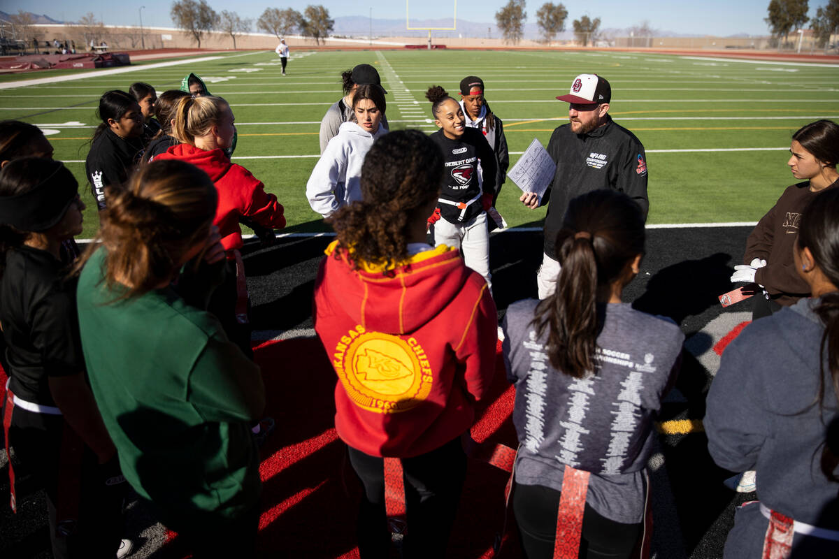 Players huddle with head coach Todd Thomson during a flag football practice at Desert Oasis Hig ...