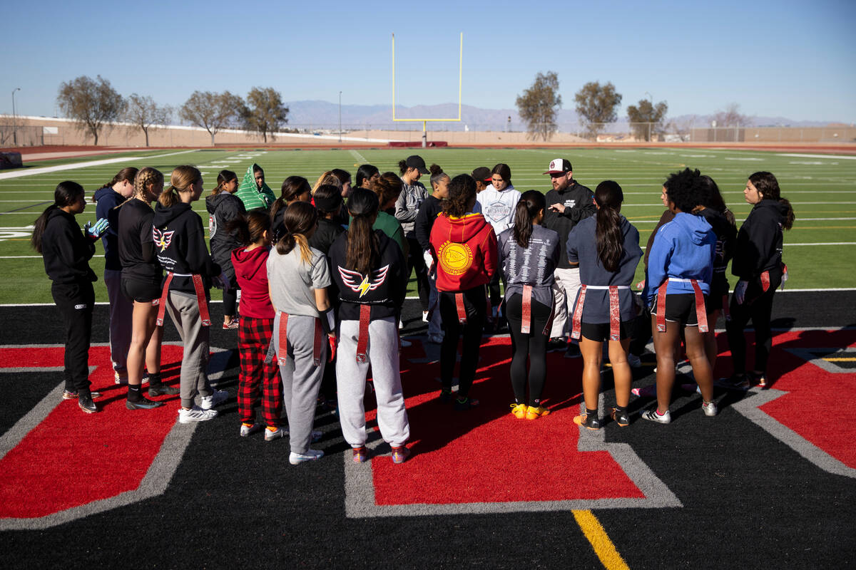 Players huddle with head coach Todd Thomson during a flag football practice at Desert Oasis Hig ...