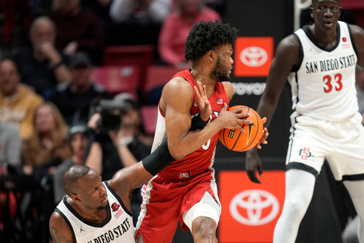 UNLV guard EJ Harkless, center, pulls the ball away from San Diego State guard Adam Seiko durin ...