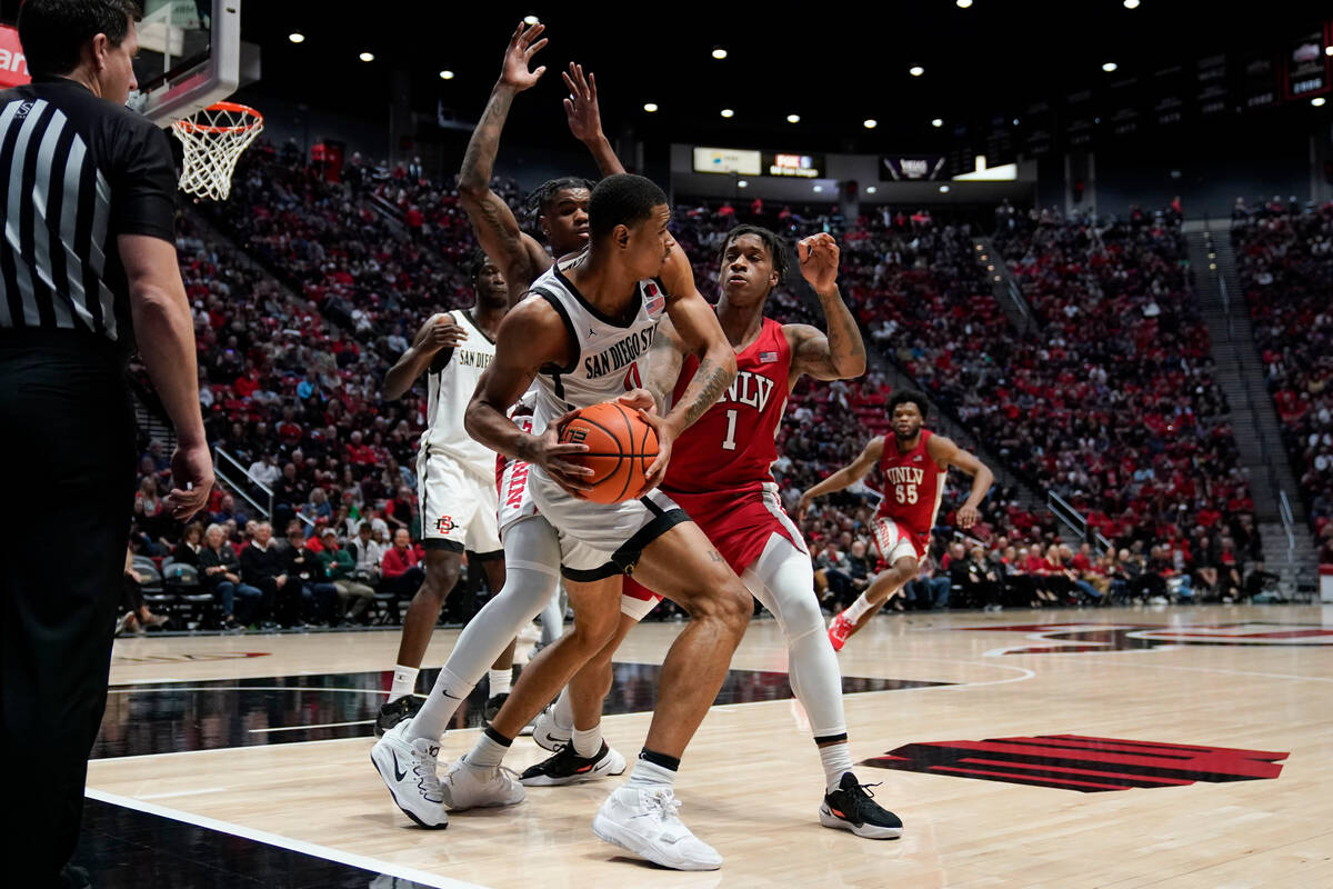 San Diego State forward Keshad Johnson, center, looks to pass as UNLV guard Elijah Parquet, rig ...