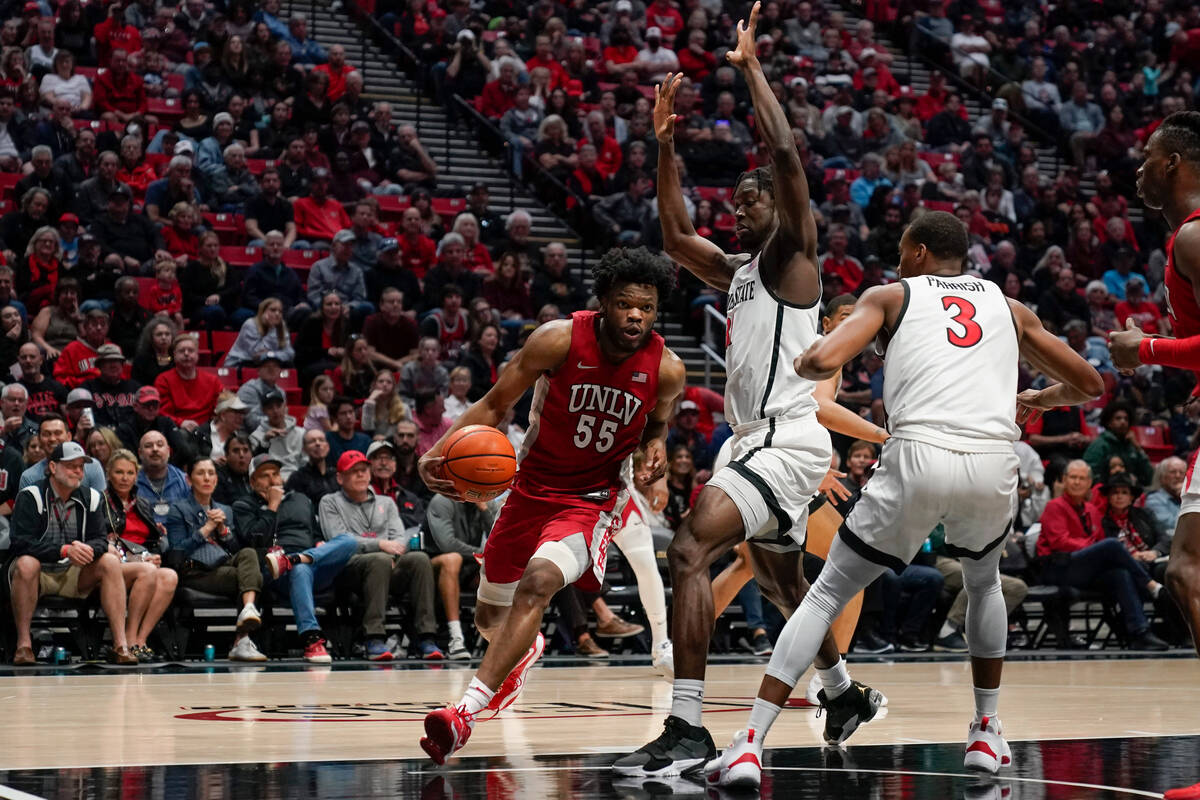 UNLV guard EJ Harkless, left, drives to the basket as San Diego State forward Nathan Mensah, ce ...
