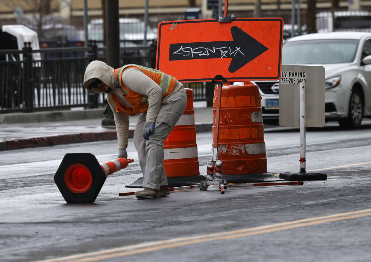 A worker fixes traffic cones that were knocked down by windy weather, Tuesday, Feb. 14, 2023, i ...