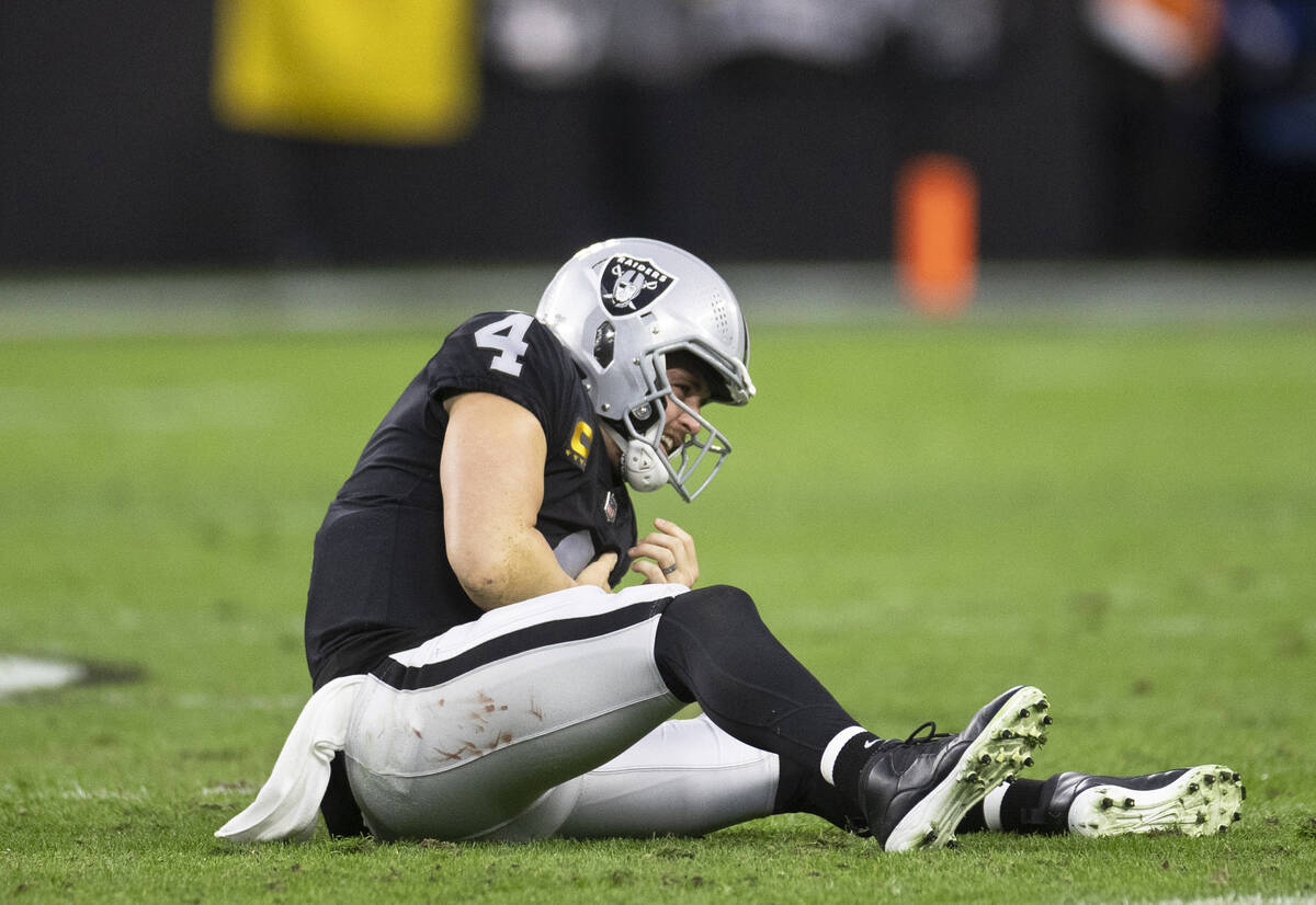 Raiders quarterback Derek Carr (4) holds his arm after being strip sacked in the second half of ...