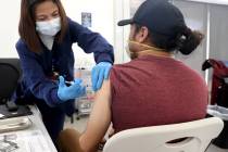 Maria Mendoza gives a shot to Javier De La Torre of Las Vegas at a COVID-19 vaccination station ...