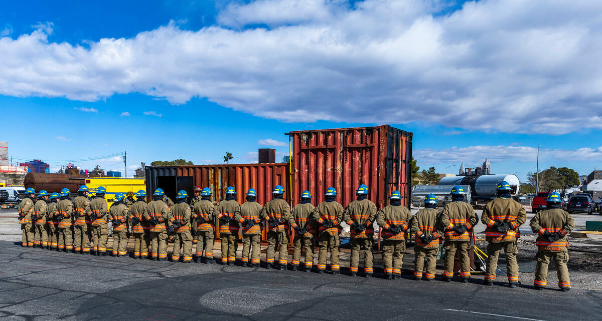 Clark County Fire Department recruits stand dressed in their turnout gear listening to instruct ...