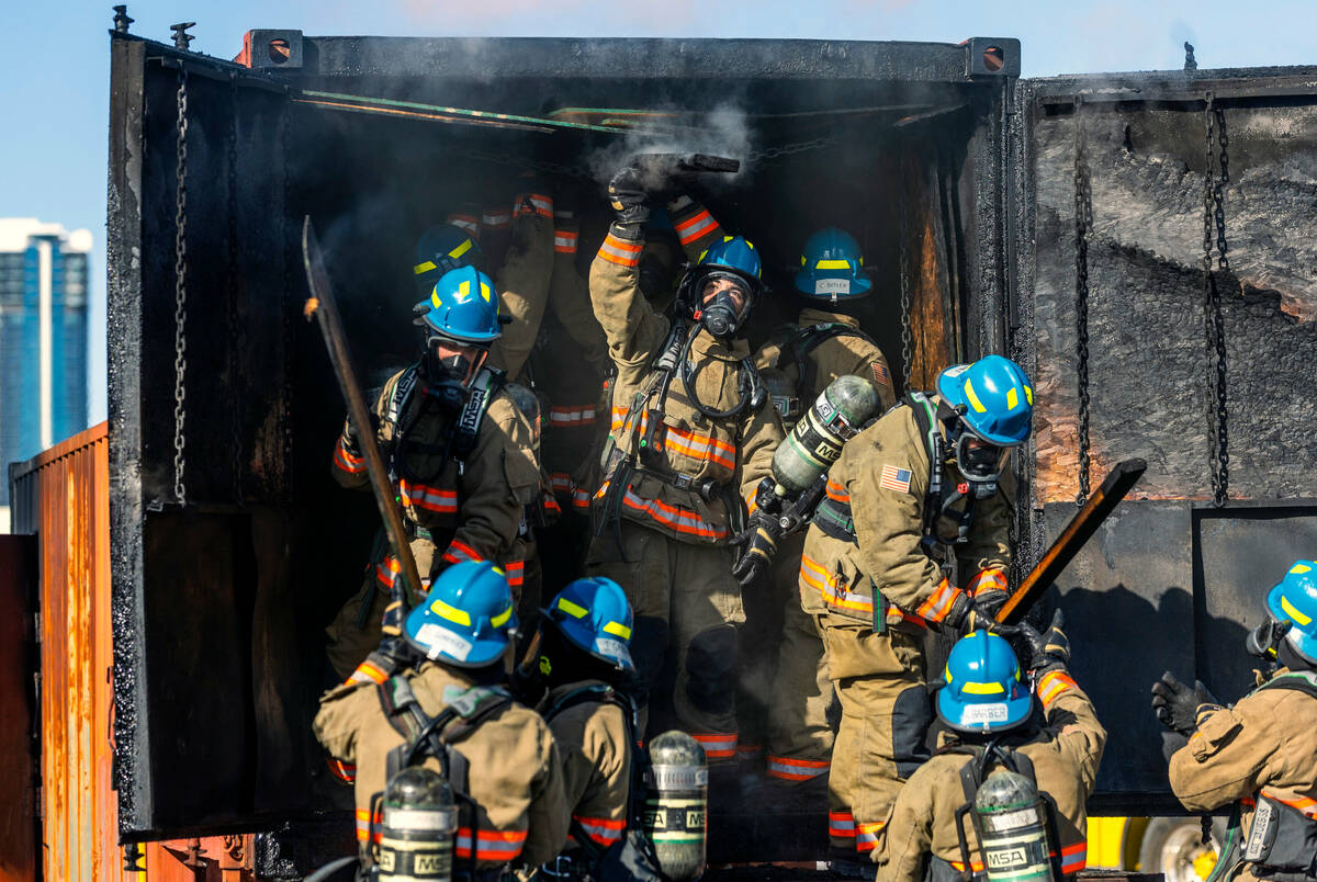 Clark County Fire Department recruits remove burnt material from a smoky trailer during live fi ...