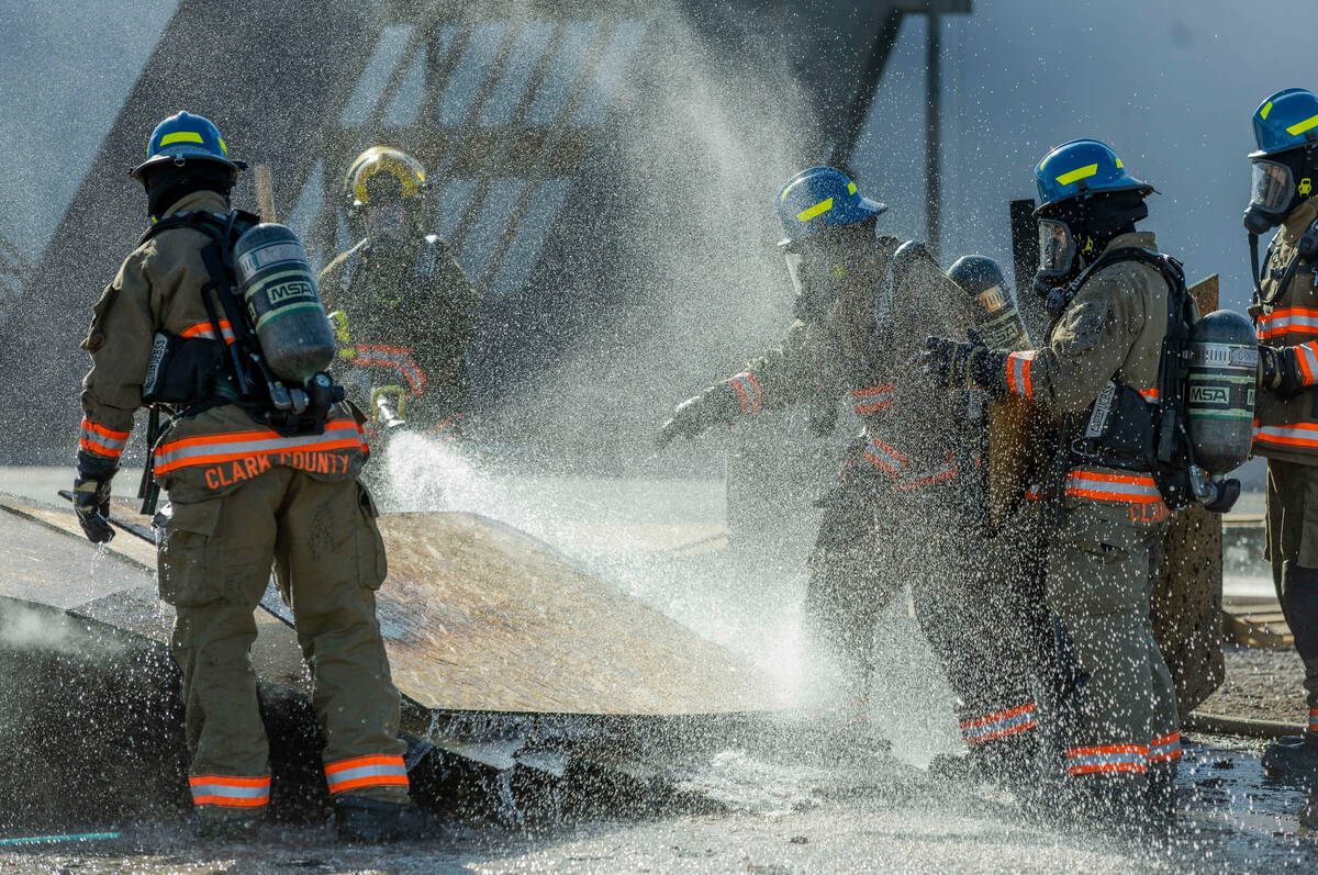 Clark County Fire Department recruits extinguish burnt material from a smoky trailer during liv ...