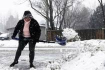 Taja Cantlon clears chunks of snow left by a snowplow from out of her driveway entrance Tuesday ...