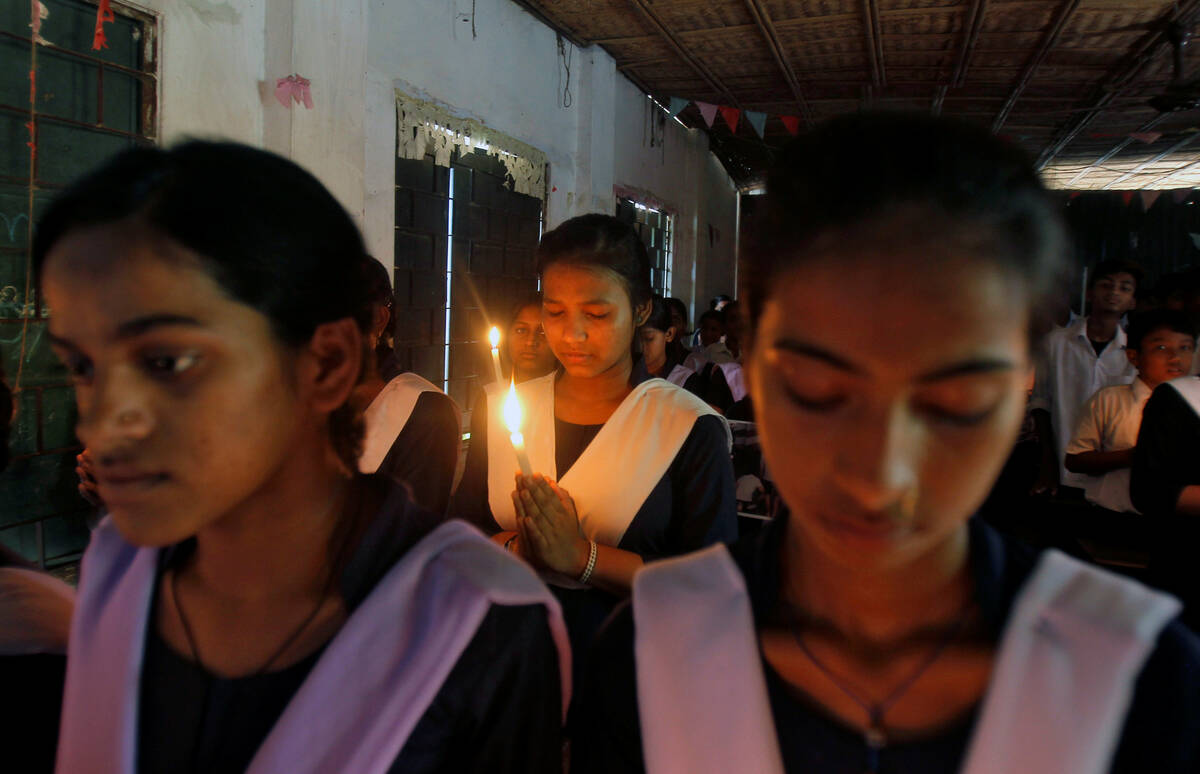 Schoolchildren hold candles as they pray during a vigil to show solidarity with the victims of ...