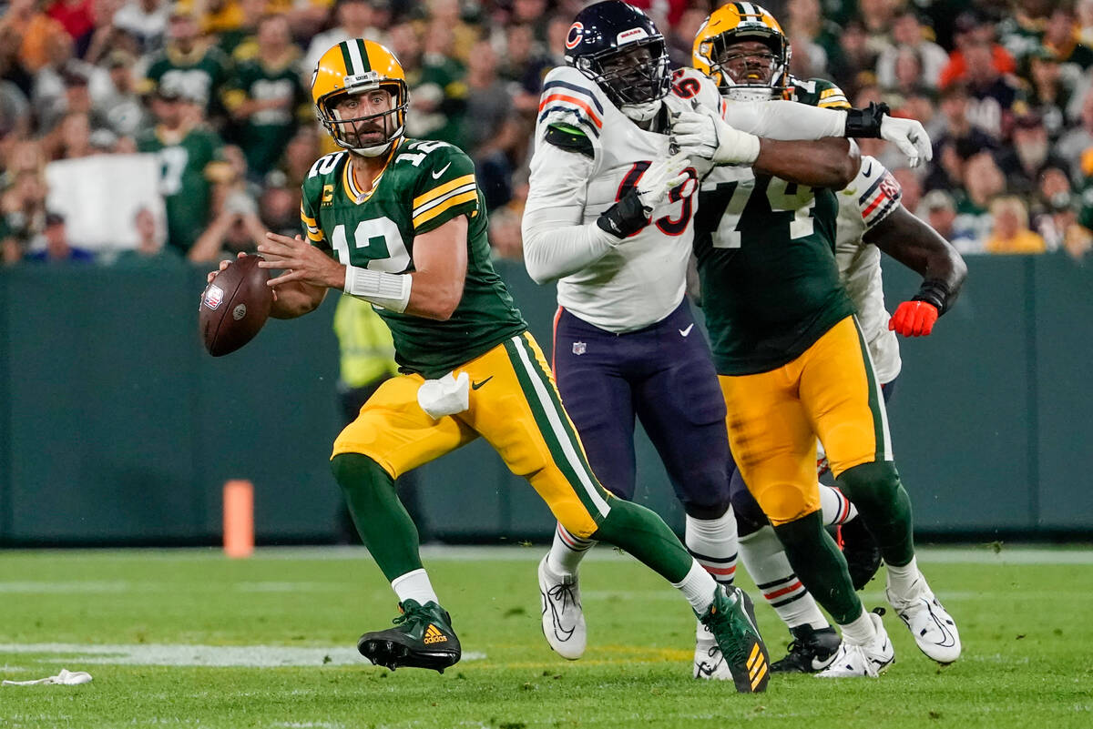 Green Bay Packers' Aaron Rodgers scrambles during the first half of an NFL football game agains ...