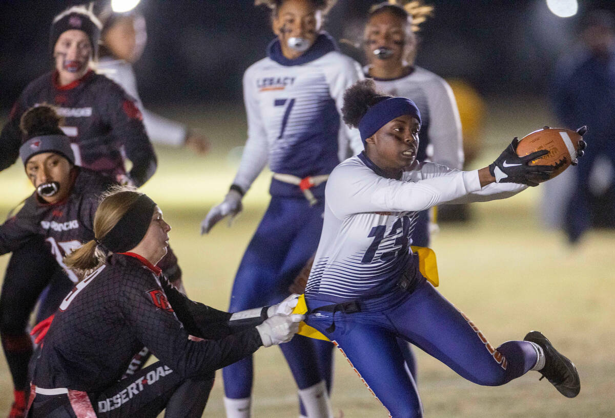 Desert Oasis' Kaylin DeLespinasse (9) pulls the flag of Legacy's Mailaya Taylor (13) as she ru ...