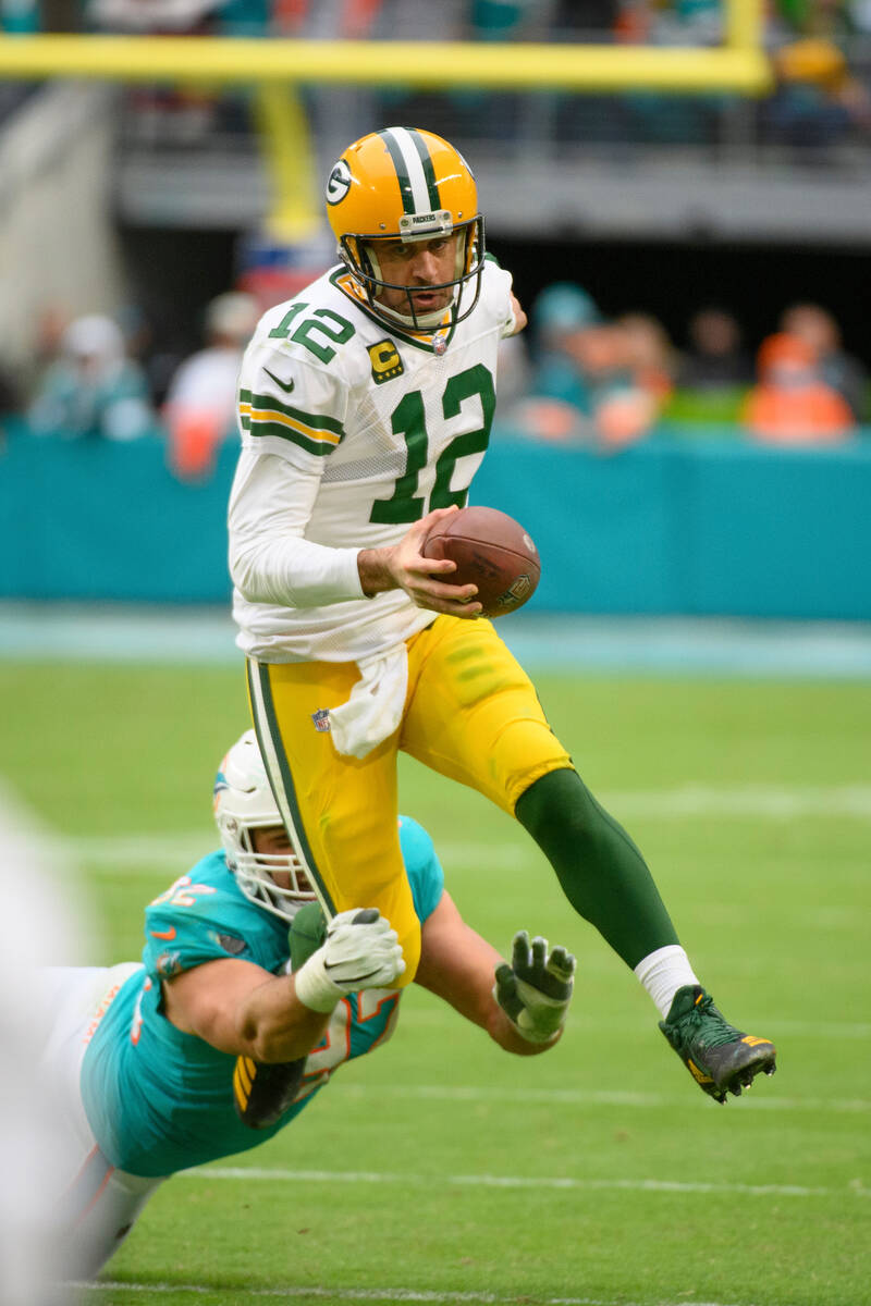 Green Bay Packers quarterback Aaron Rodgers (12) runs with the ball and jumps in the air to avo ...