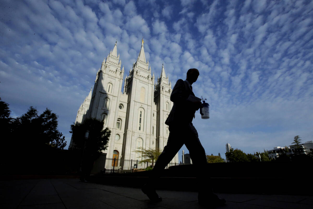 A man walks past the Salt Lake Temple, a temple of The Church of Jesus Christ of Latter-day Sai ...