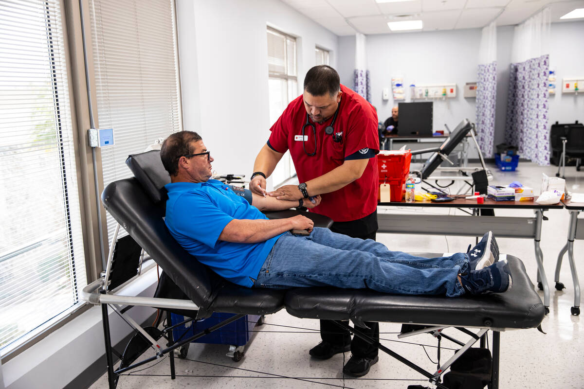 Dan Perez, American Red Cross collections technician, prepares to draw blood from John Martinez ...