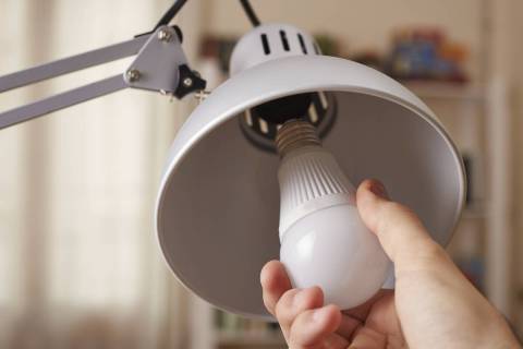 Hand changing a regular light bulb for LED. (Thinkstock)