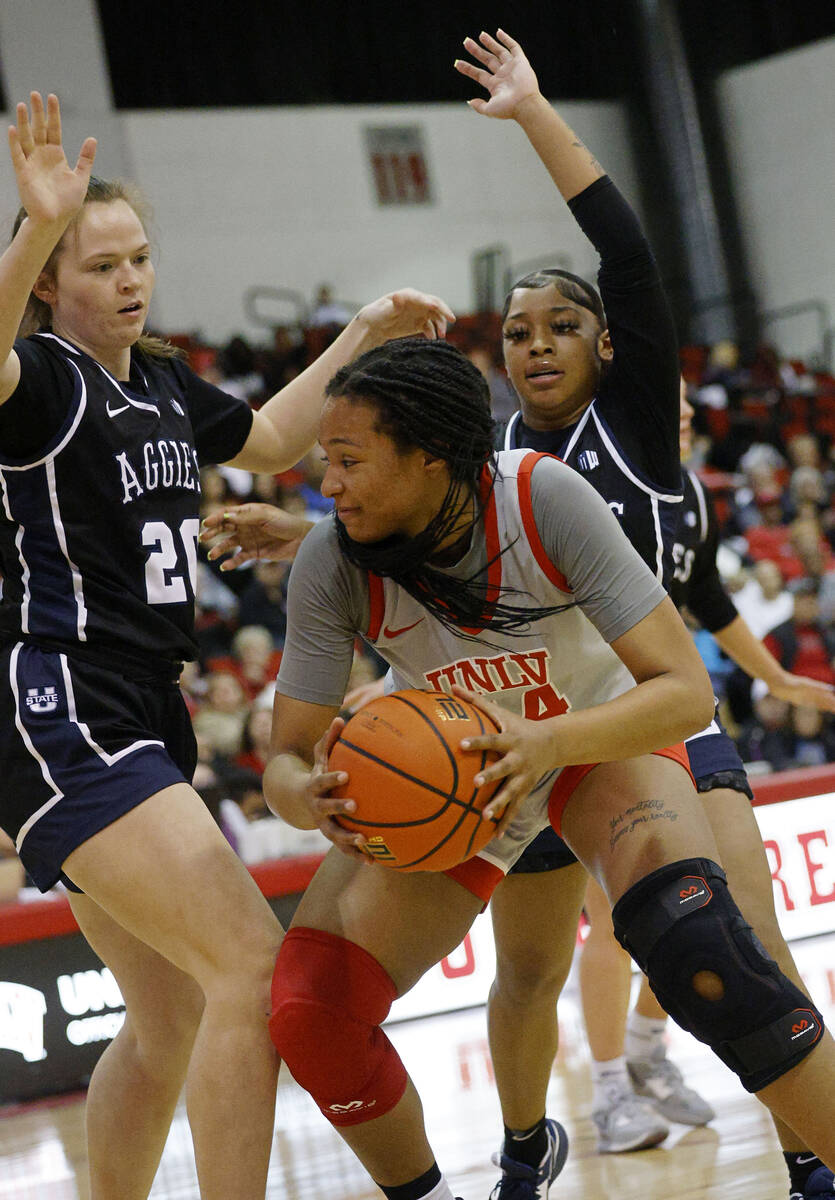 UNLV Lady Rebels forward Alyssa Brown (44), center, keeps a ball away from Utah State Aggies fo ...