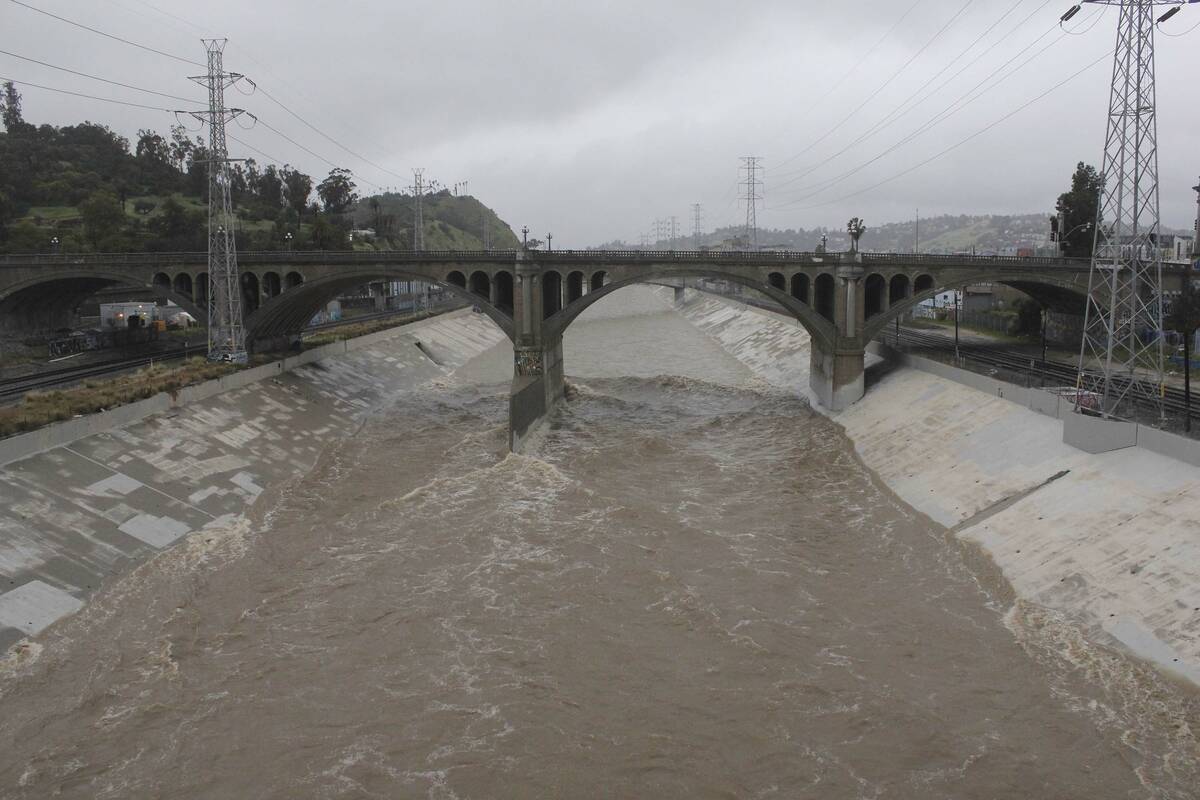 The rain-swollen Los Angeles River flows near downtown Los Angeles on Saturday, Feb. 25, 2023, ...