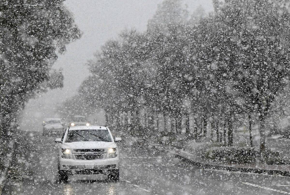 A vehicle makes its way across Wilson Avenue in Rancho Cucamonga, Calif., as snow begins to bla ...