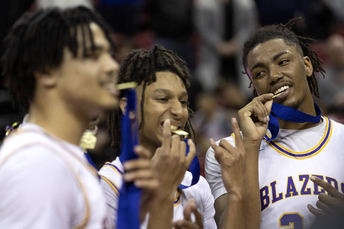 Durango players Michael Bartlett, left, Mason Brown and Taj Degourville bite their medals for w ...