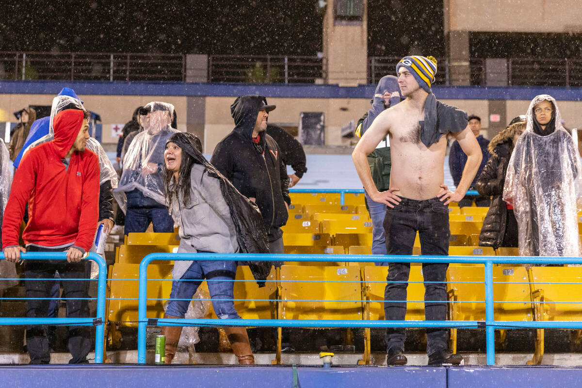 Fans stay to watch the teams play as rain pours during the second half of an XFL football game ...