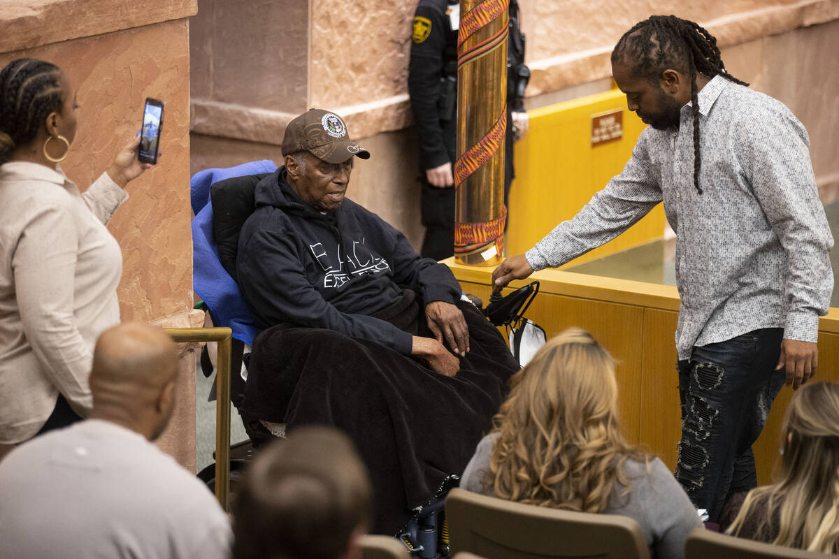 Retired Las Vegas police officer Herman Moody, 97, is guided by his grandson Damian Moody to be ...