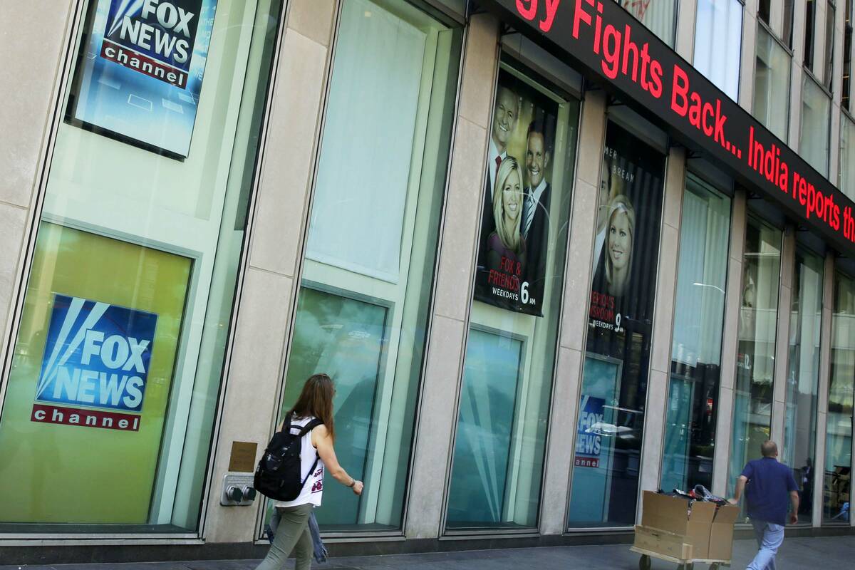 People pass the News Corporation headquarters building and Fox News studios in New York on Aug. ...