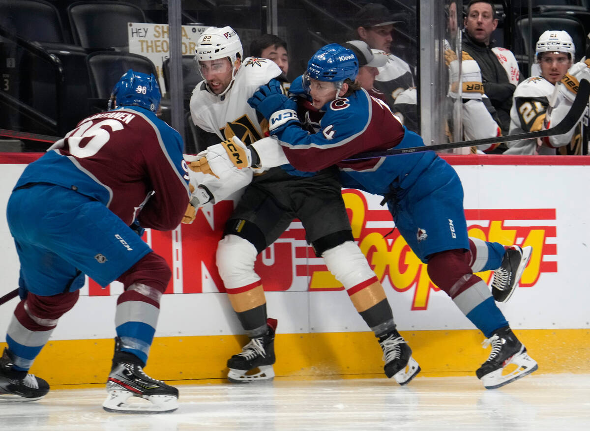 Vegas Golden Knights right wing Michael Amadio, center, is checked by Colorado Avalanche defens ...