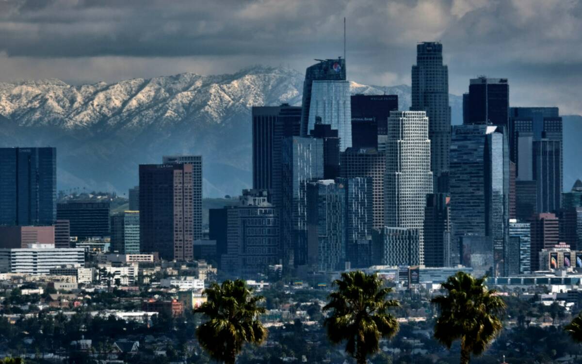 Storm clouds and snowfall are seen over the San Gabriel mountain range behind downtown Los Ange ...