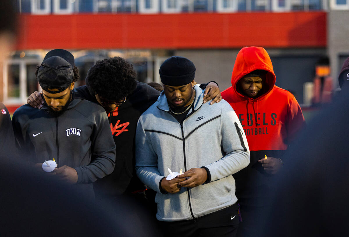 Participants bow their heads while standing on the 47-yard lines on the field at Rebel Park at ...
