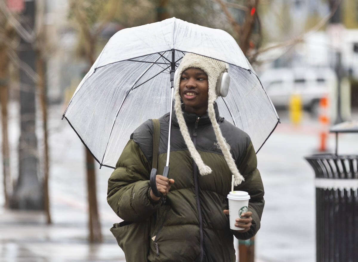 A pedestrian holds an umbrella to protect himself from rain as he walks along East Boneville Av ...