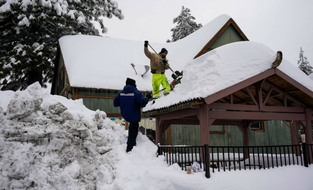 Kevin Maze, top, and Donnie Smith remove snow from a structure in Running Springs , Calif., Tue ...