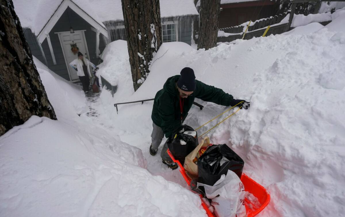 Angie Gourirand walks down the snow-covered steps of her home with groceries on a sled in Runni ...
