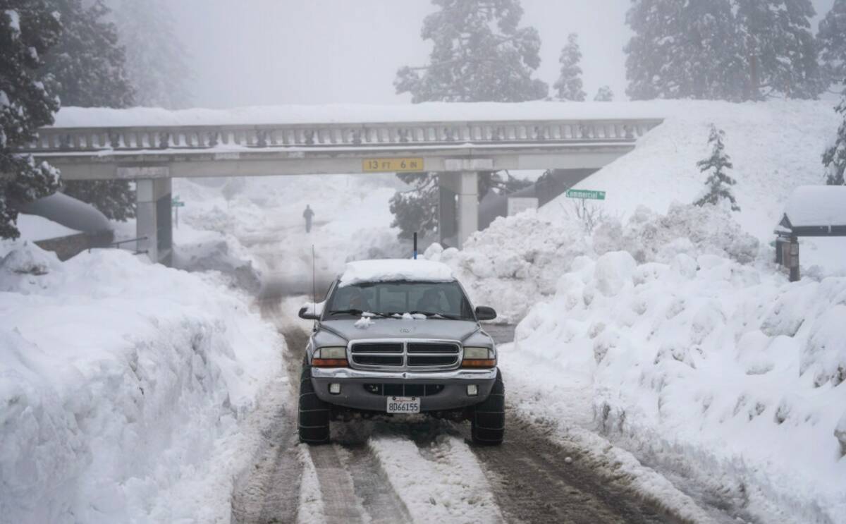 A truck drives along snow berms in Running Springs, Calif., Tuesday, Feb. 28, 2023. (AP Photo/J ...
