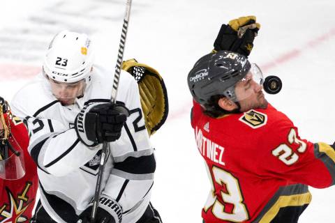 Golden Knights defenseman Alec Martinez (23) takes a puck to the face while defending as Kings ...
