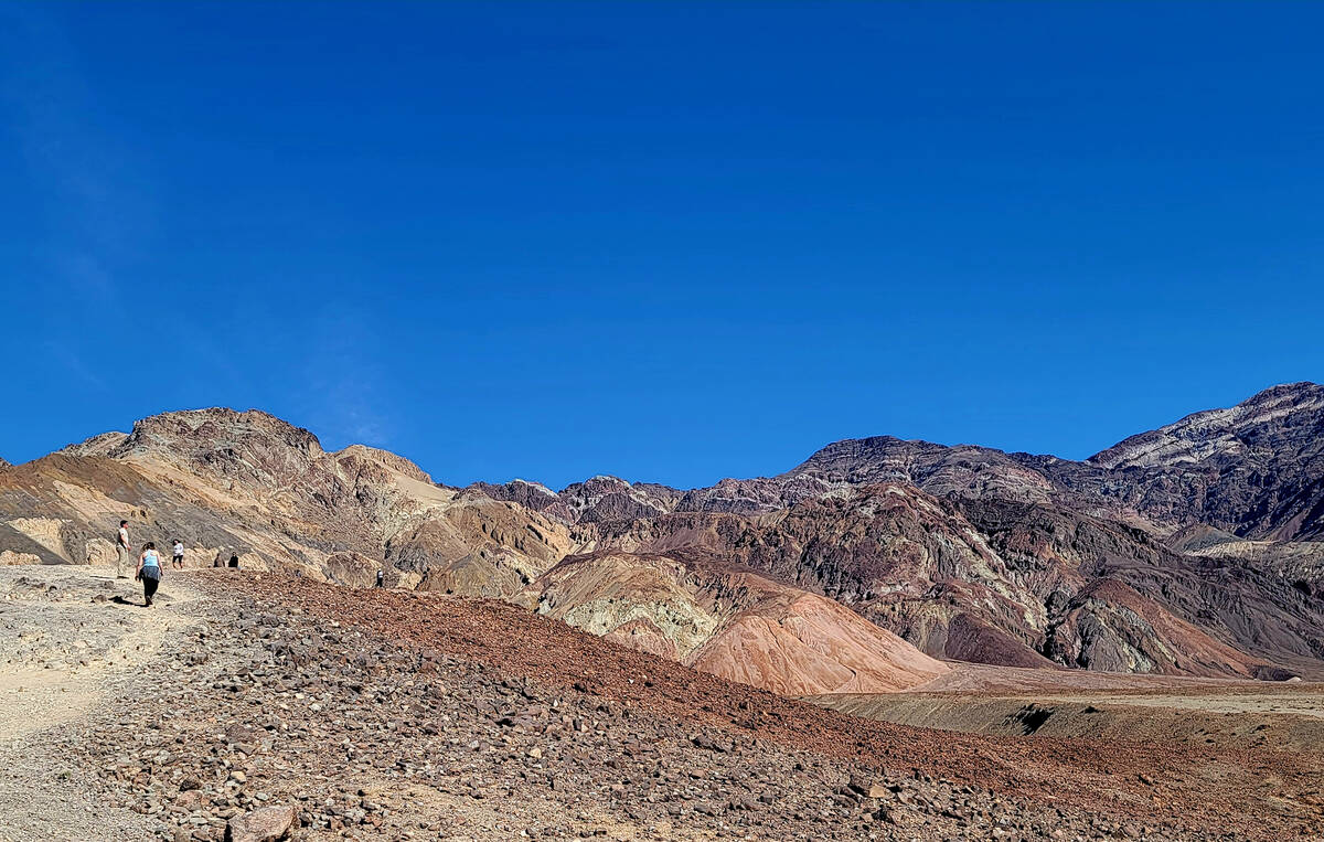 Visitors hiking uphill to enjoy stunning geology from a viewpoint along Death Valley's 9-mile, ...