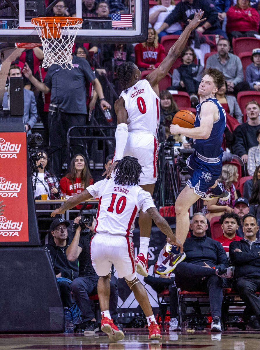 UNLV forward Victor Iwuakor (0) defends the net as Utah State guard Max Shulga (11) is forced t ...