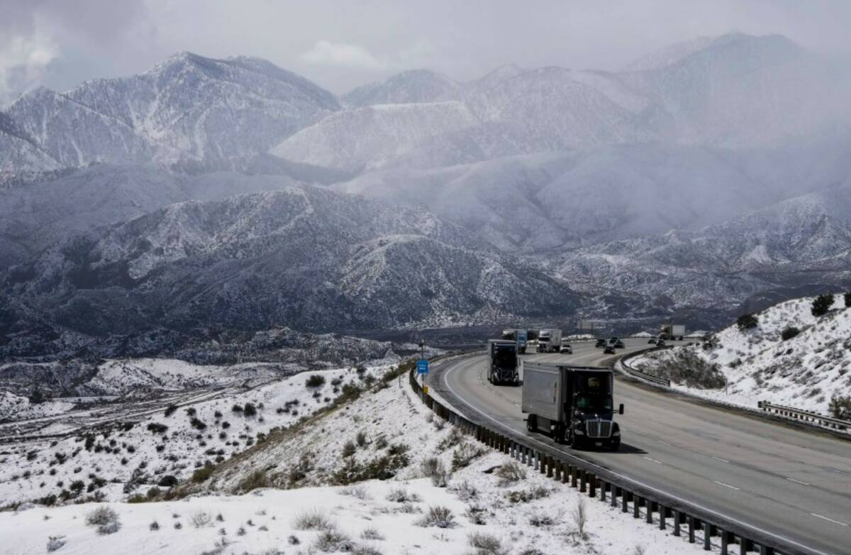 Vehicles make their way along the I-15 as clouds pass through the snow-covered mountains near H ...