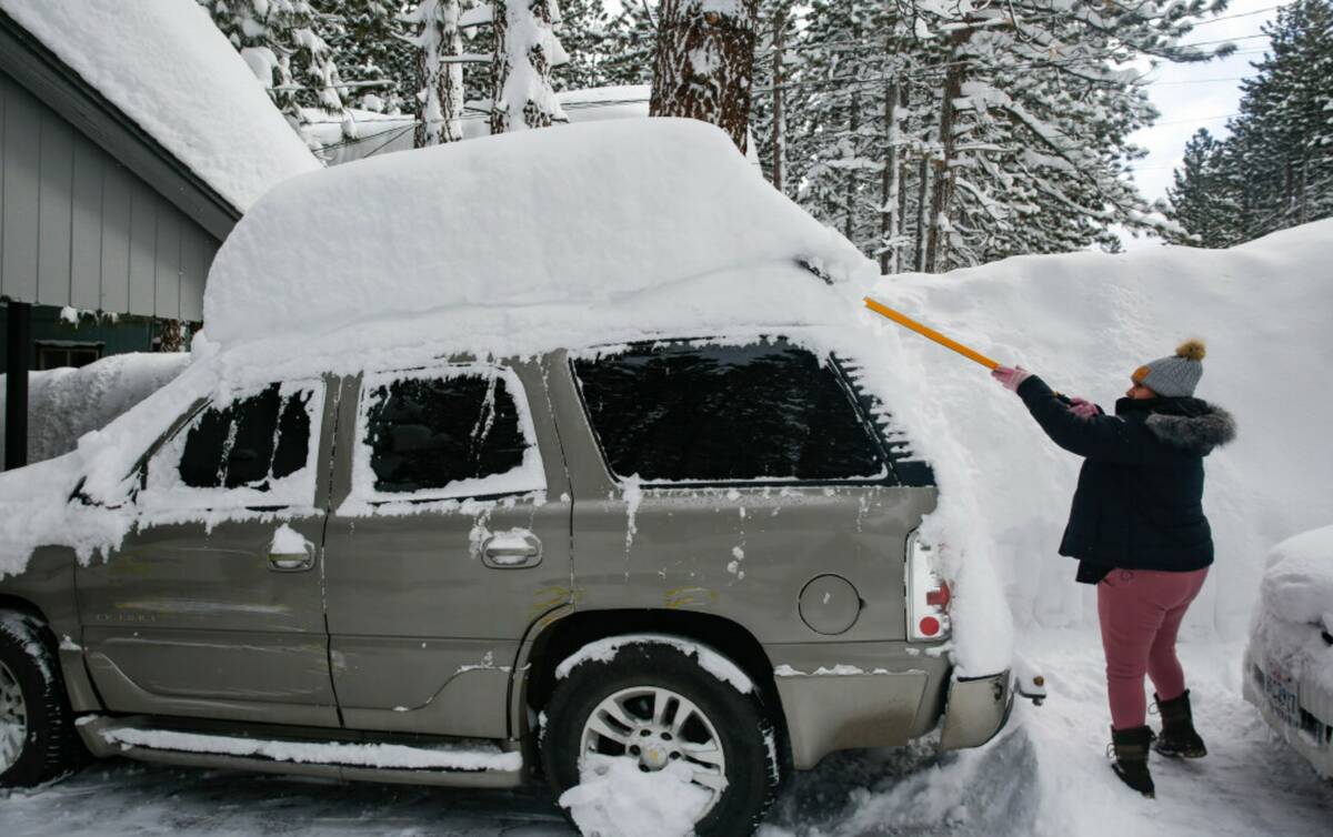 Isabelle Barbosa clears snow off her cars in front of her home along Larch Avenue in South Lake ...
