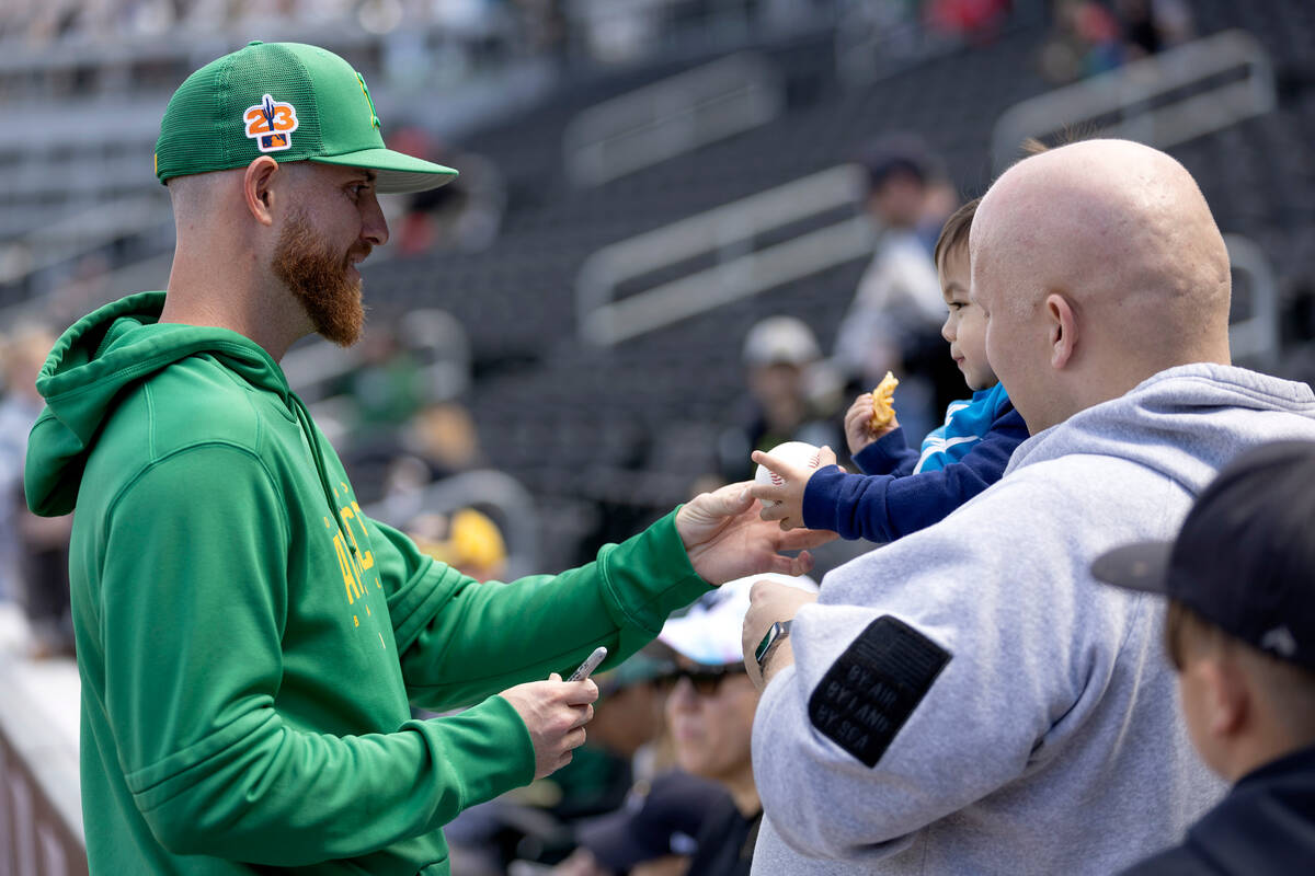 The Oakland Athletics’ Paul Blackburn signs an autograph for JT Hardisty, 2, and his dad ...