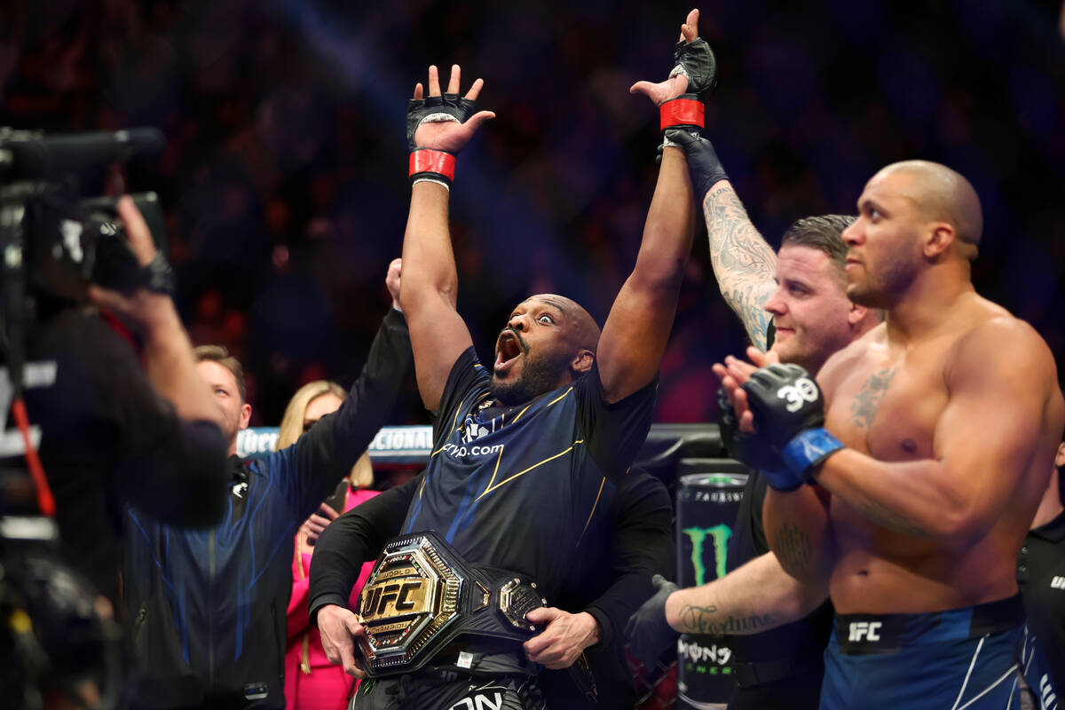 Jon Jones, left, reacts after getting announced the winner in the heavyweight title bout agains ...